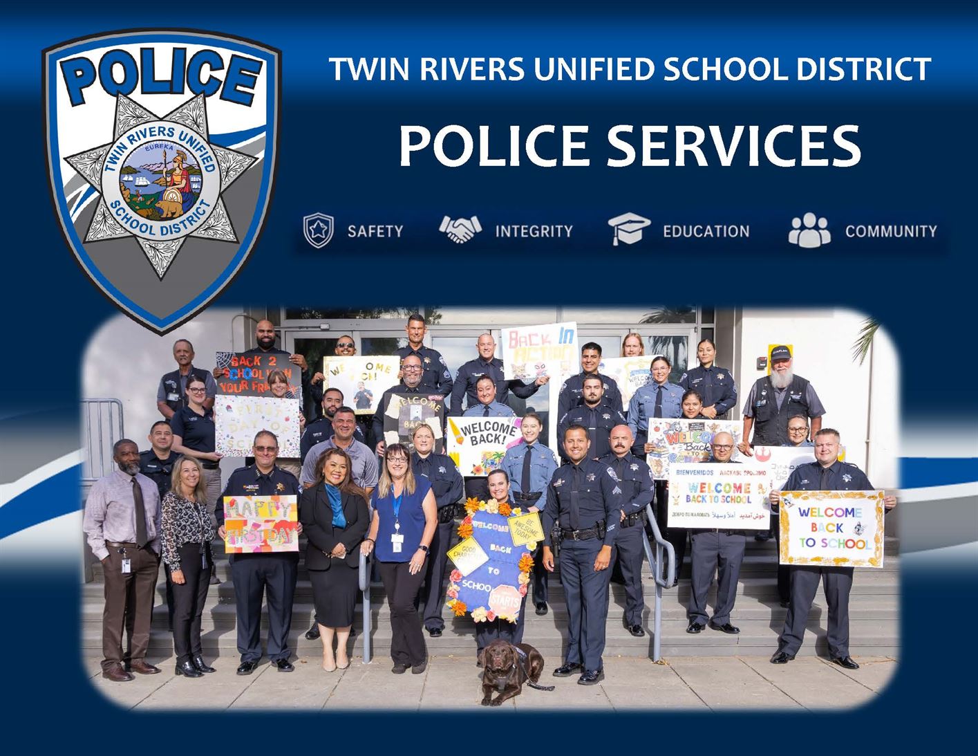 Photo of department staff holding up welcome back signs in front of Police Services building