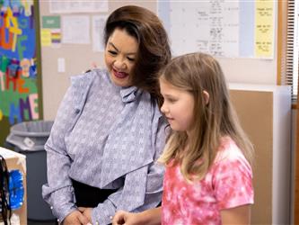 Dr. Tu Moua-Carroz and elementary student looking at a class project