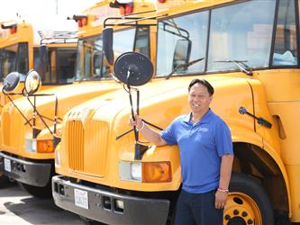 Employee of the year in front of a school bus