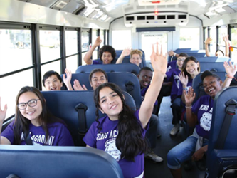 A group of kids wearing purple shirts in a school bus