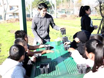 Students getting ready to put plants with soil in plastic pots