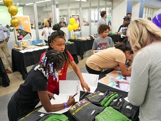 Students signing a book at the table - Literacy Night