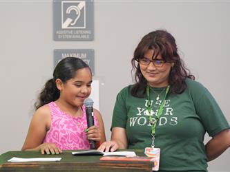 A student is reading a book with staff - Literacy Night