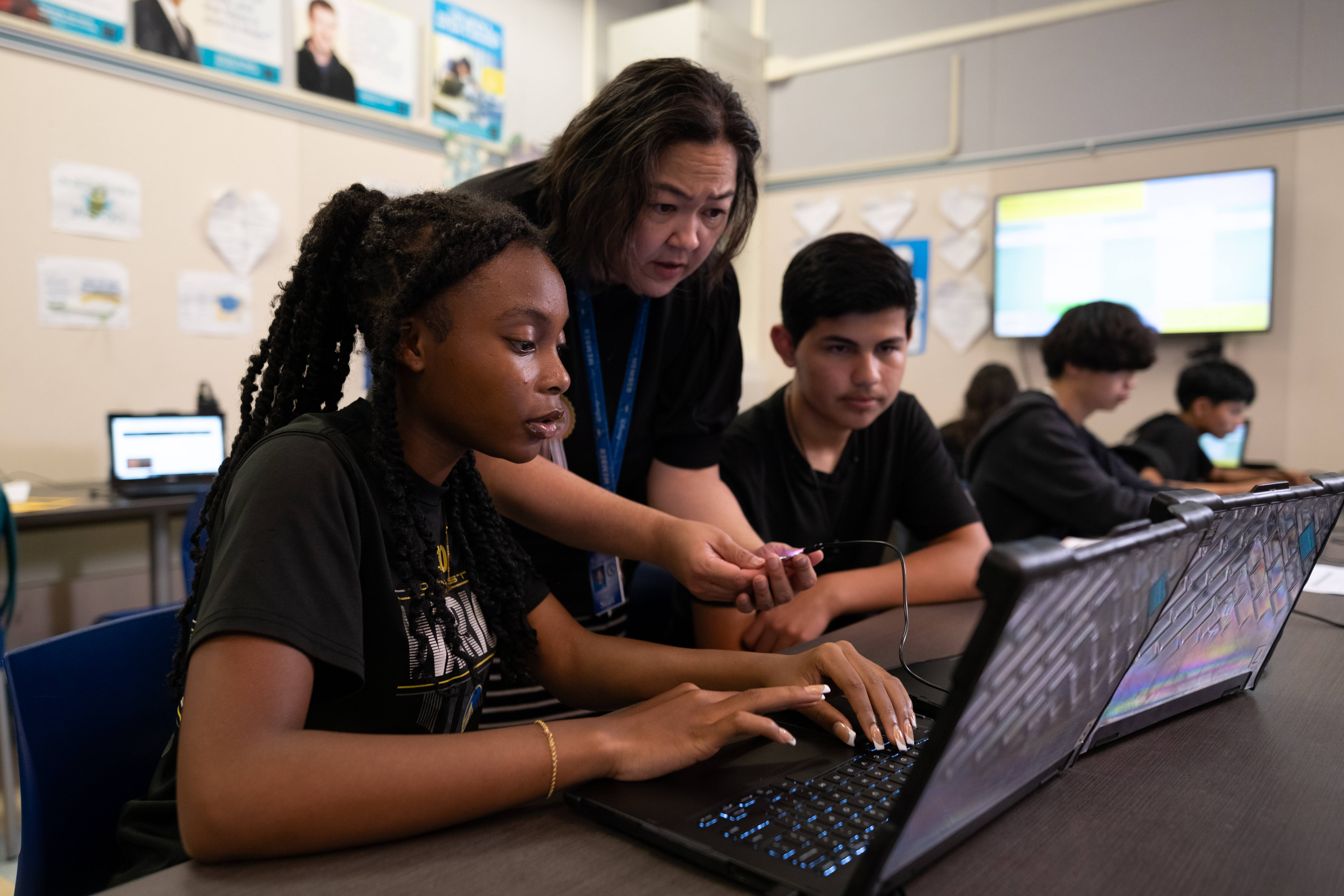 Teacher helping students with a computer program
